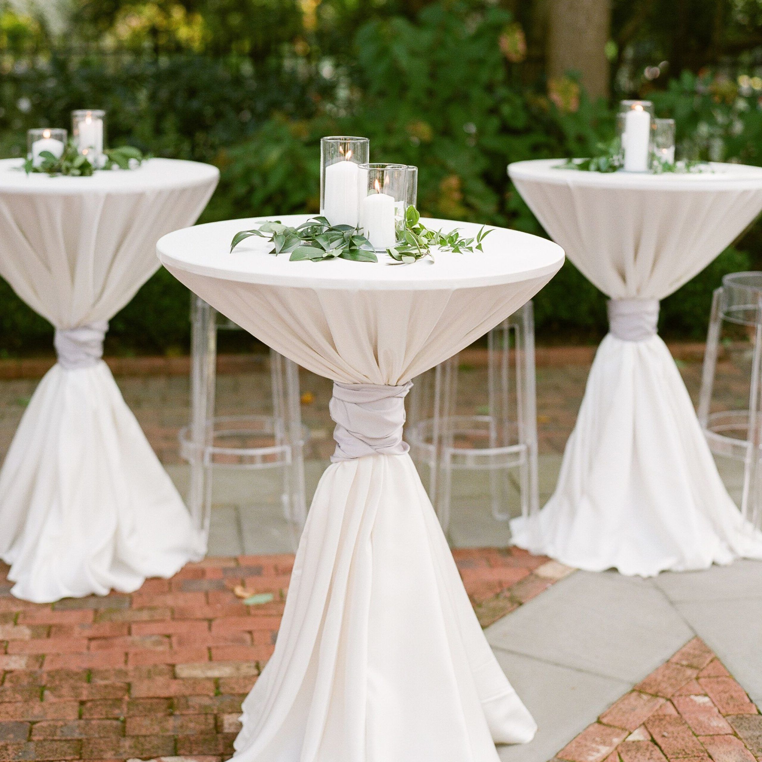 White Pillar Candles And Greenery Atop Cocktail Tables | Wedding With Regard To Natural Outdoor Cocktail Tables (View 9 of 20)